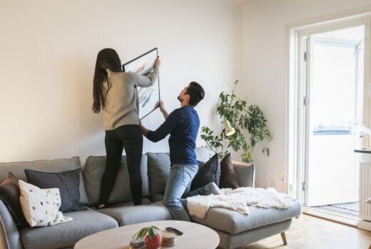 couple-adjusting-painting-on-wall-while-leaning-on-royalty-free-image-953941956-1557778874